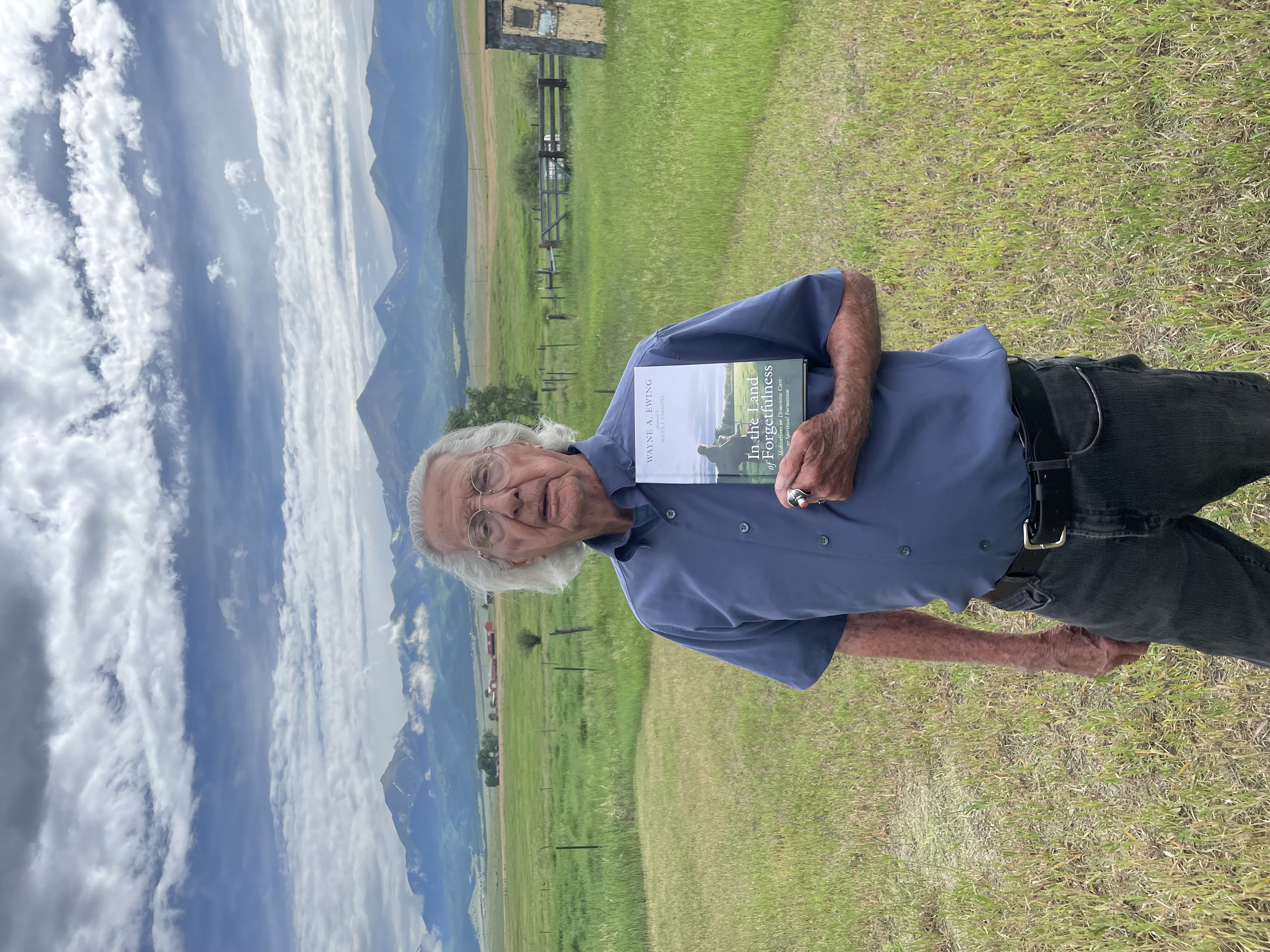Wayne holding his book with the Sangre de Cristo peaks behind him